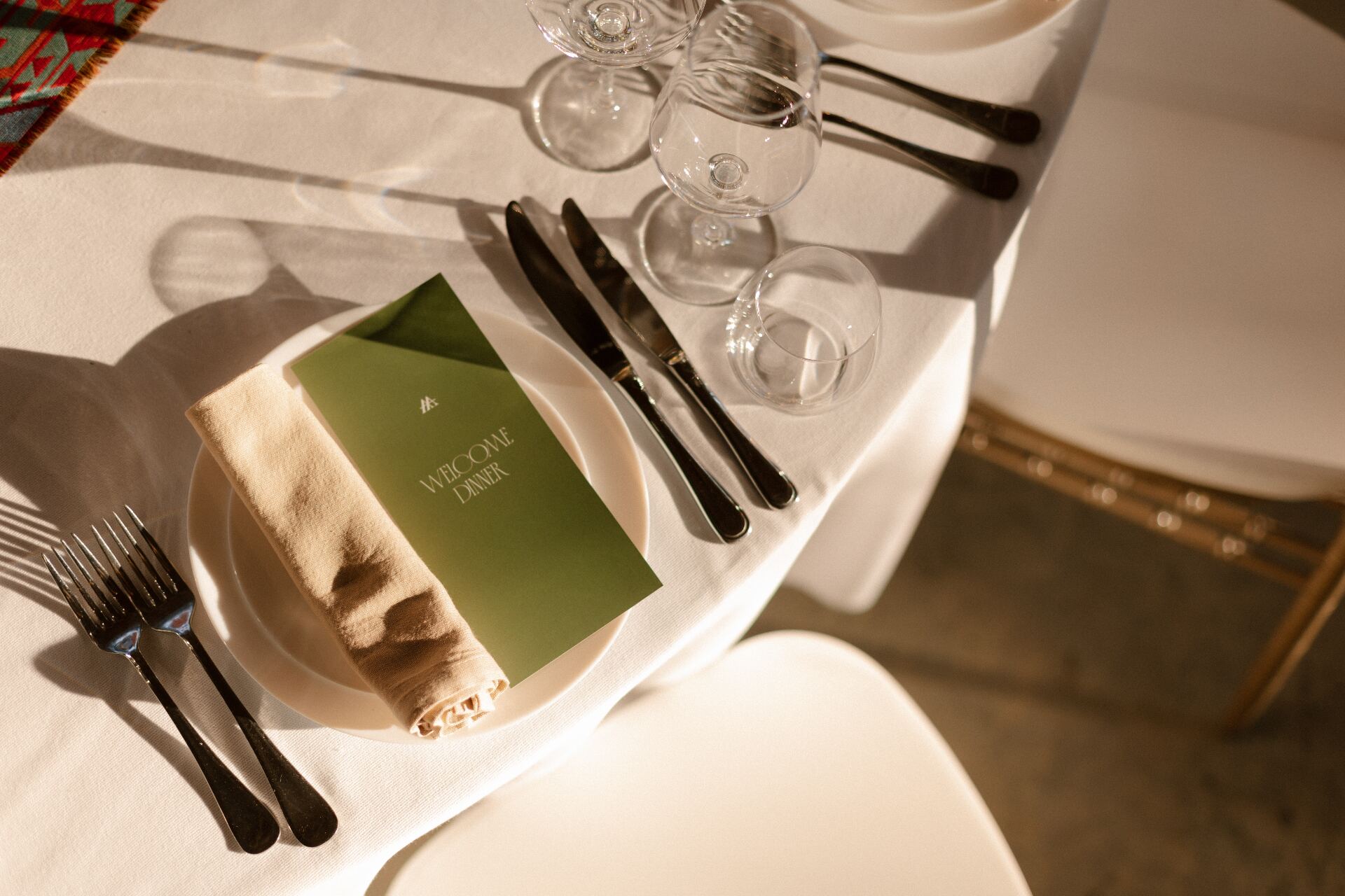 Welcome dinner place setting — green menu card on a linen napkin with crystal stemware