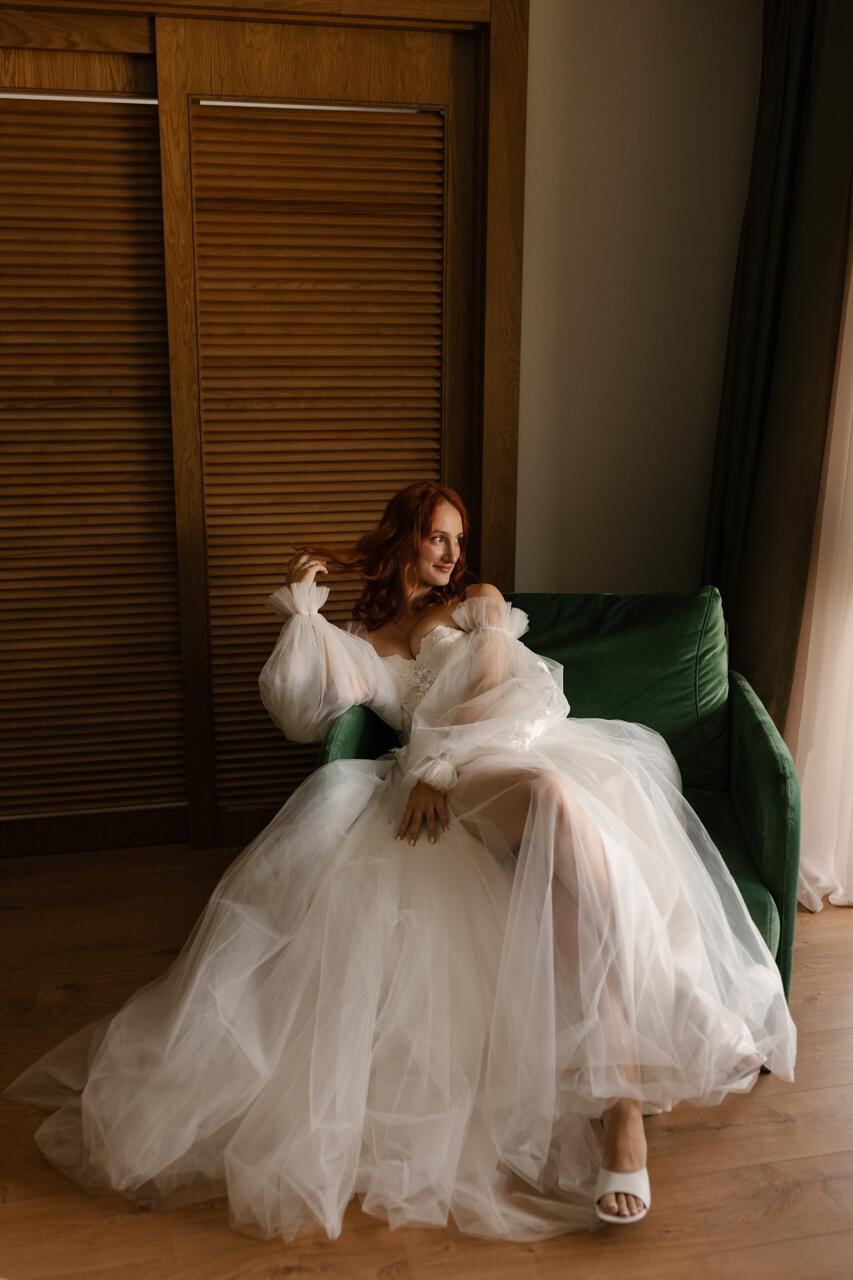 Bride portrait in a tulle gown seated on a green velvet sofa